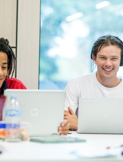 Some young people sit and chat while using laptops in the study space