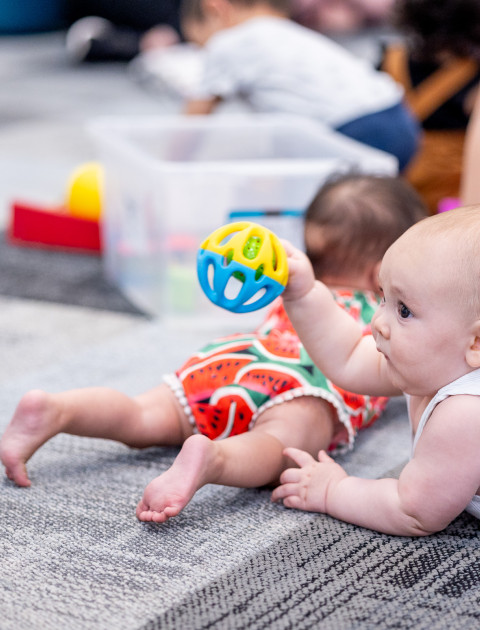 baby plays with a toy at the library