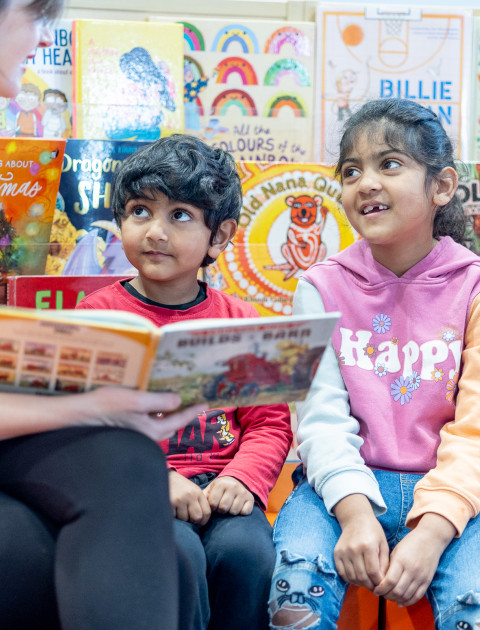 two children looking at a book with an adult