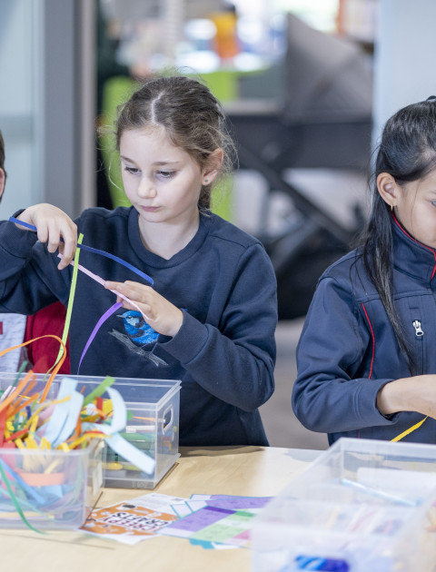Three children doing a craft activity in the library