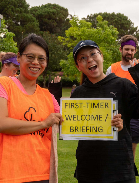 two people holding a sign saying First-time welcome/ briefing