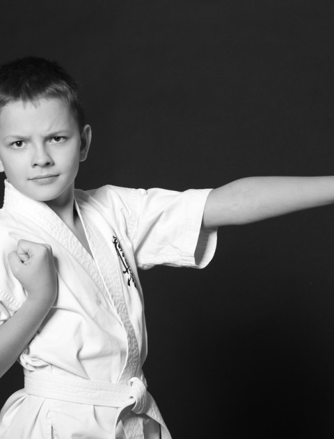 a boy in a karate outfit is standing with one hand straight to look like a punch