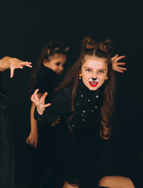 a group of girls are dressed in black with cat make-up and acting at the camera
