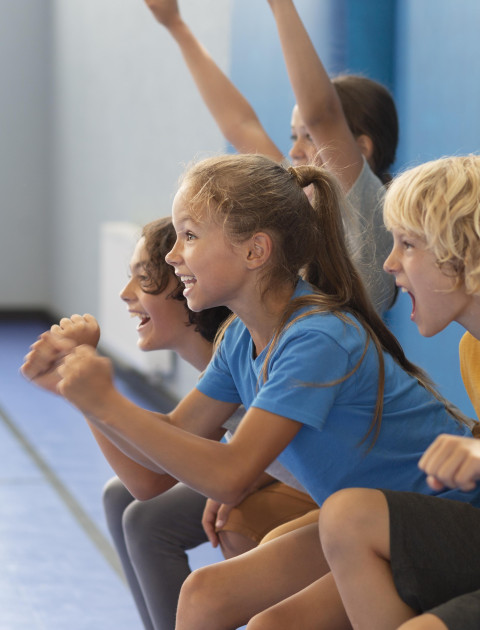 children are doing squats leaning against a wall and cheering
