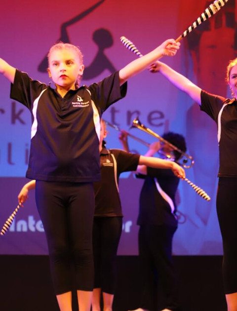 a group of girls dressed in black are standing on a stage with their arms held high