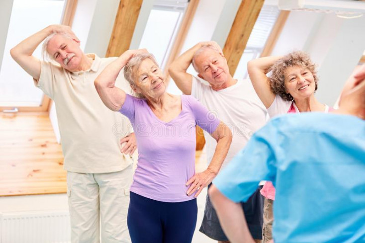 a group of older people are standing with their hand on their head pulling it to the side