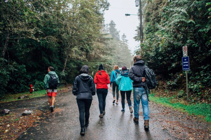 a group of people wearing different coloured rain jackets walk down a street away from the camera