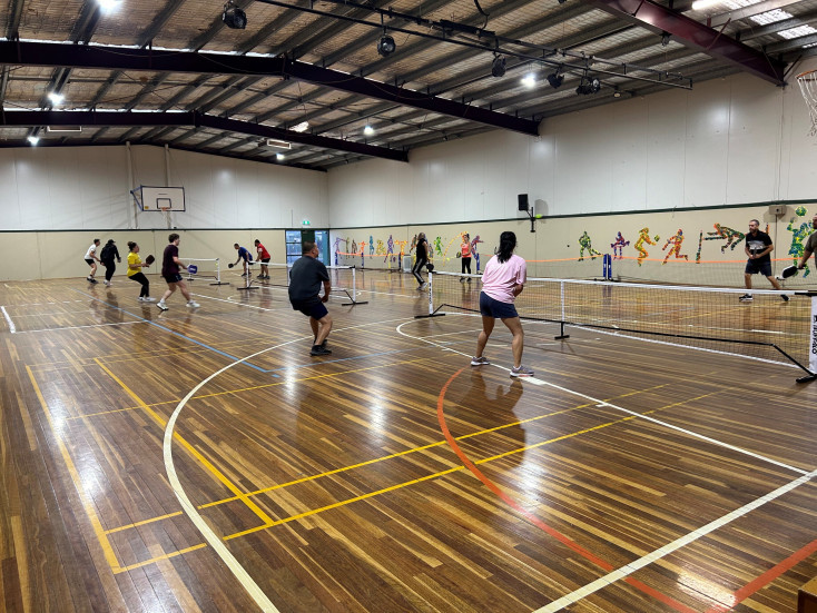 a group of people are playing pickleball indoors