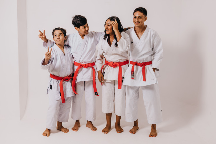 a group of teenage boys and girls wearing karate suits smile at the camera