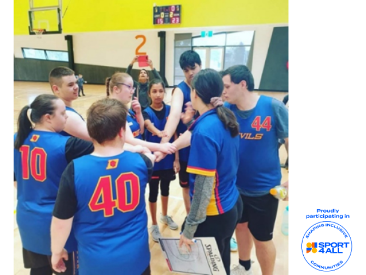 a group of people wearing blue basketball tops with red numbers on the back are standing in a circle. They have their hands in the middle.