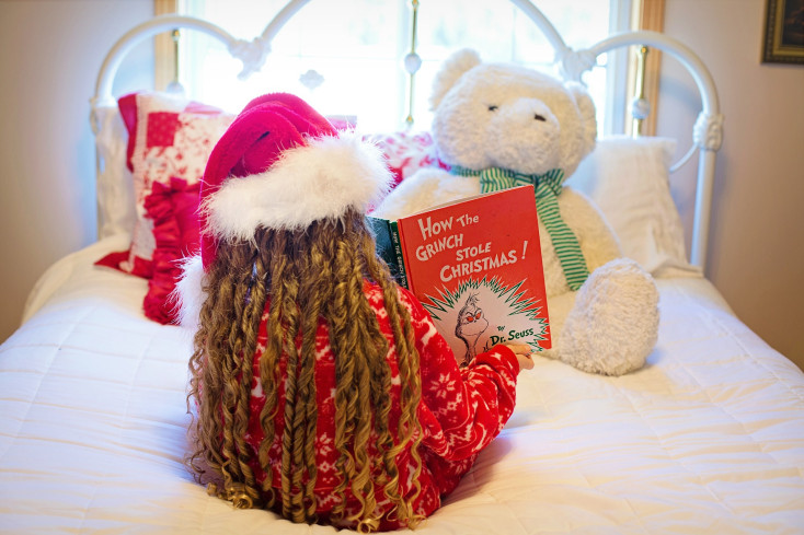 Girl reading christmas book to a bear