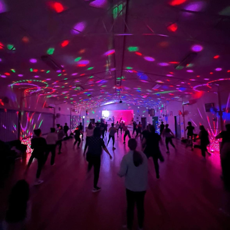 a dark room with multi coloured disco lights and people dancing