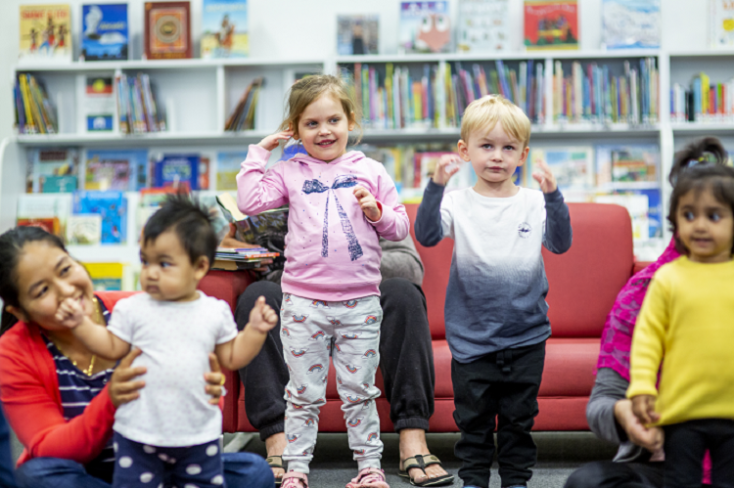 Children and parents singing and dancing together in the library.