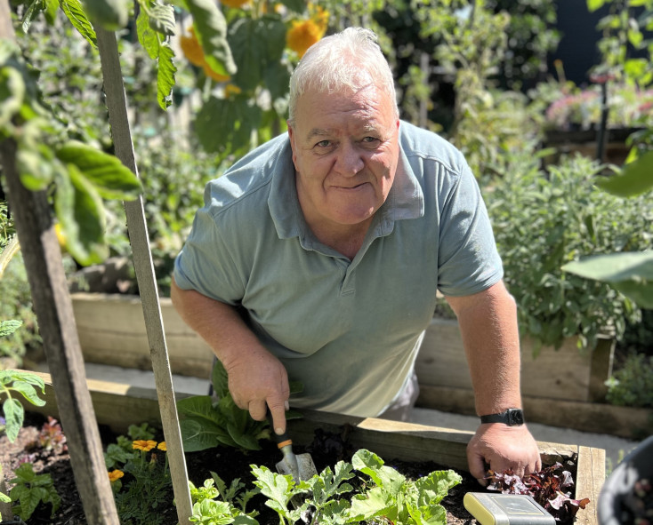 Craig in his garden surrounded by growing veggies. 