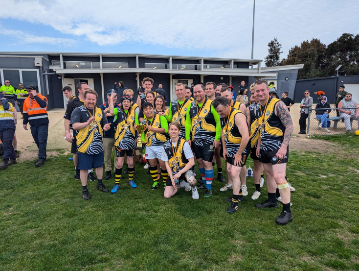 a group wearing yellow sports tops are smiling at the camera