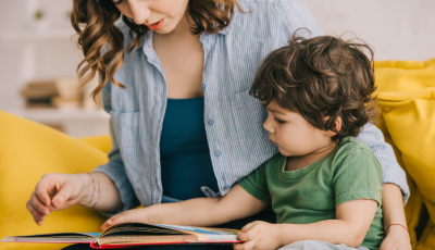 Image of woman reading picture book together with child.