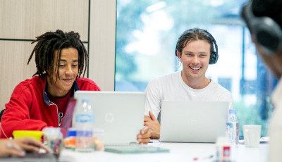 Some young people sit and chat while using laptops in the study space