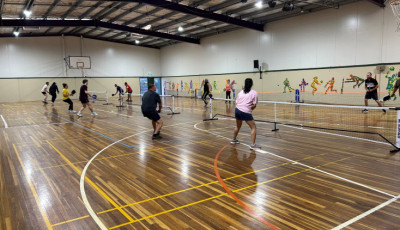 a group of people are playing pickleball indoors