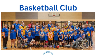 a large group of kids and adults wearing blue basketball kits are smiling at the camera.