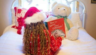 Girl reading Christmas book to bear