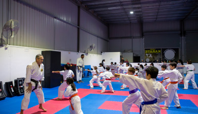 a group of people wearing karate uniforms are facing an instructor