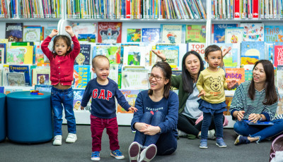 Parents and children singing and smiling in the library.