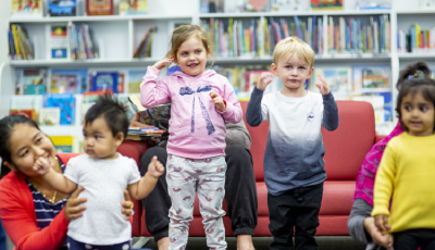 Children and parents singing and dancing together in the library.