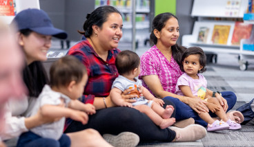 Mothers and children sitting on the floor in the library.
