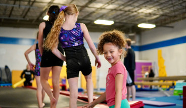 kids are climbing onto gym equipment in a queue and smiling