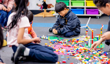 Children and parents sitting on the floor in the library and building with Lego.
