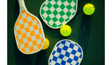 three brightly coloured bats: orange, blue and green and two yellow balls