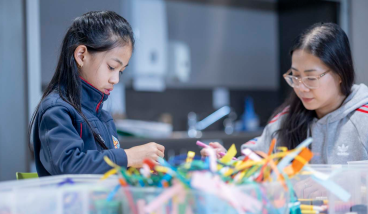 2 people making craft with paper strips