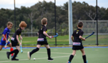 Children participating in a hockey session on an outdoor field